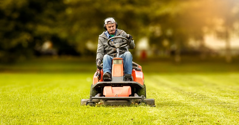 Person drives lawnmower over large yard