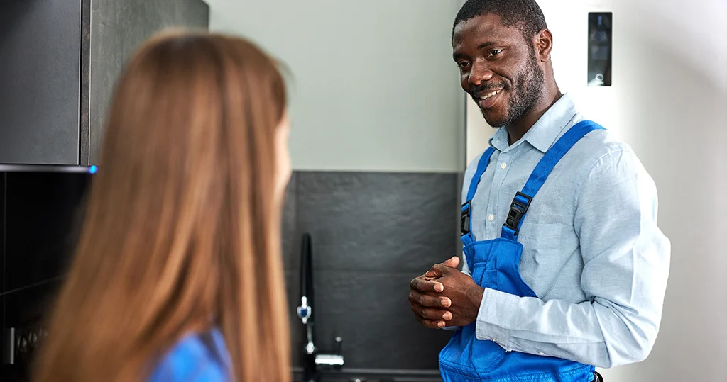 Plumber talks to client in front of kitchen sink