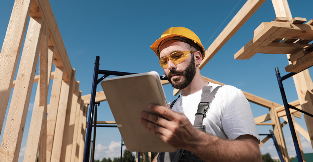 Pro on roof of frame house, using a tablet