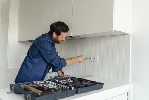 Professional electrician using a screwdriver while installing a new electrical socket.