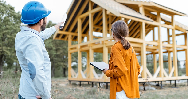 Residential construction project manager with client in front of construction site