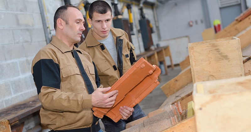 Roofer and apprentice discussing roof tile