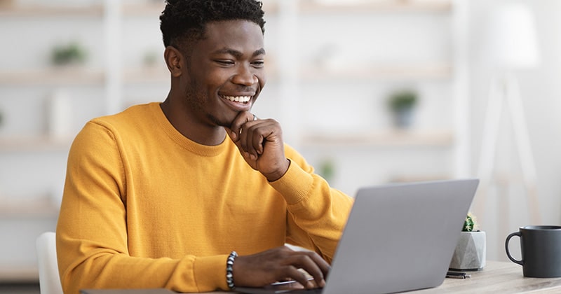 rade pro smiling and writing content on laptop