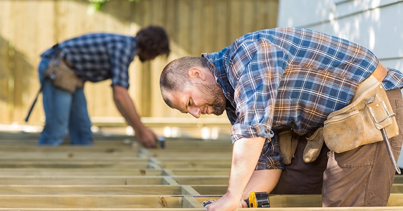 Two carpenters working on building deck outside home