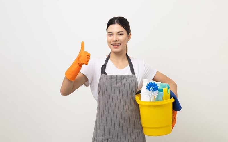 Young housekeeper woman holding bucket of cleaning products ready for cleaning home