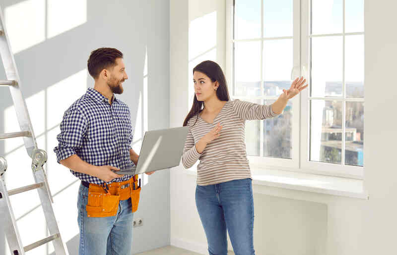 Young woman talking to a repairman who is going to make repairs in her house