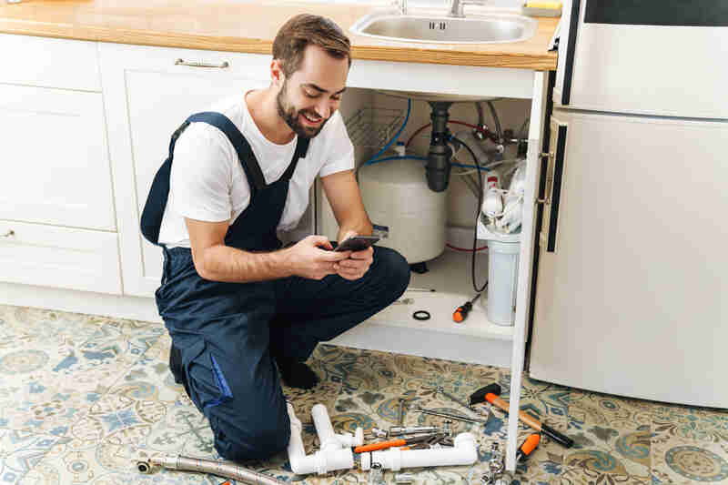plumber in uniform indoors using mobile phone
