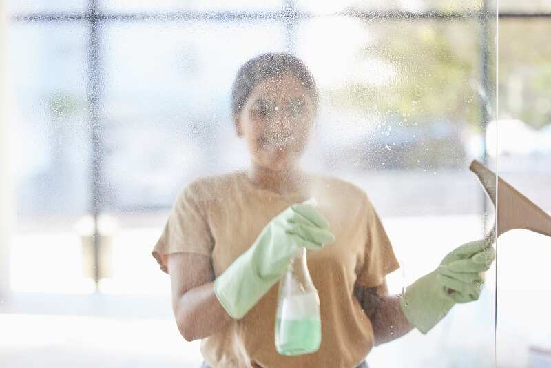 woman and cleaning window with smile spray bottle and soap
